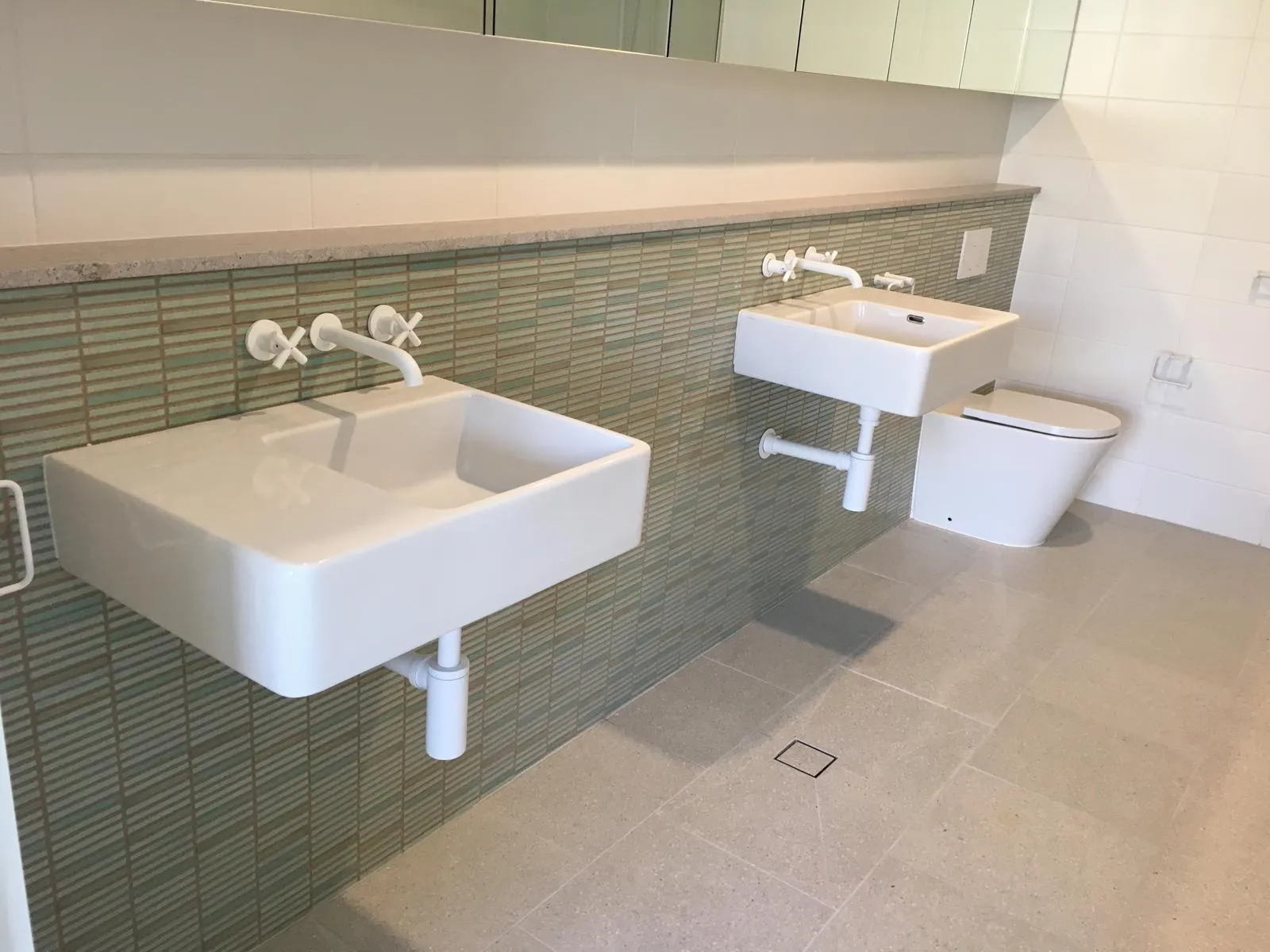 Completed bathroom renovation with green feature tiles